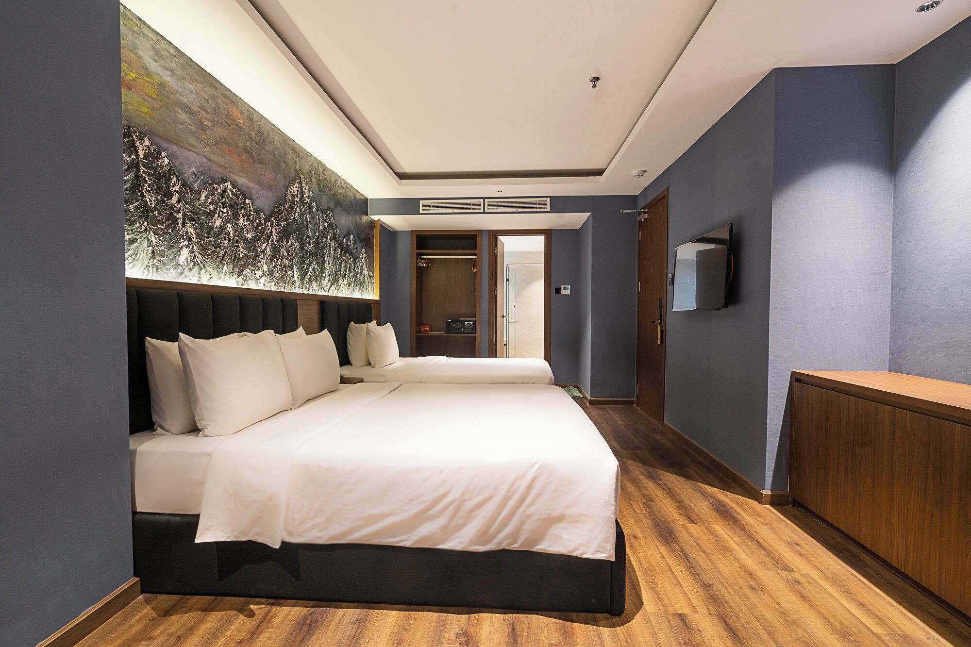 A hotel room with a large bed, a flat-screen TV, and a painting on the wall.
