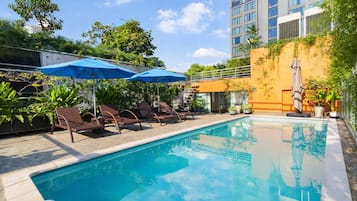 Una piscina al aire libre, sillones reclinables de piscina