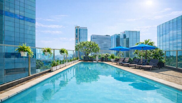 A rooftop pool with clear blue water, surrounded by lounge chairs and umbrellas, with modern buildings in the background.