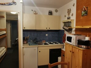Eine kompakte Küche mit Herd, Mikrowelle und kleinem Kühlschrank.