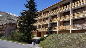 A multi-story building with balconies, a mountain in the background, and a road in the foreground. - Studio 38m², 6 pers, pets allowed, near slopes (Orcières Merlette)
