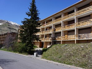 A multi-story building with balconies, a mountain in the background, and a road in the foreground. - Studio 38m², 6 pers, pets allowed, near slopes (Orcières Merlette)