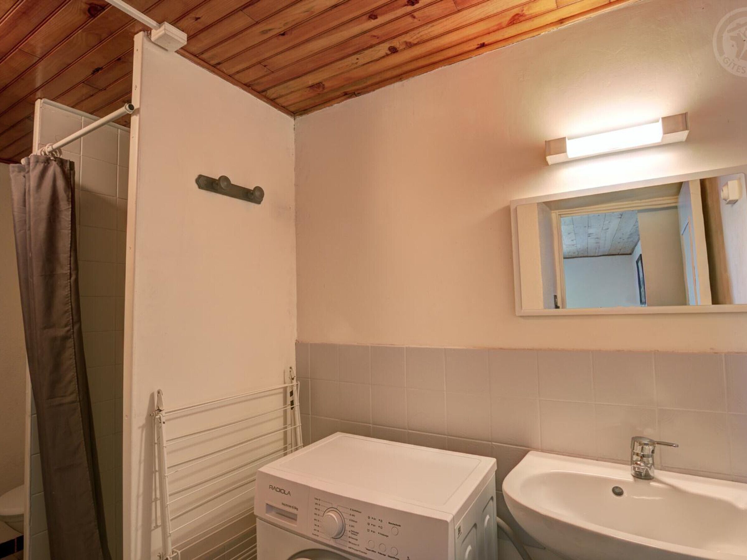 Un baño pequeño con lavadora, lavamanos y espejo.