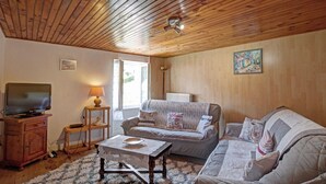 A cozy living room with wooden ceilings, a sofa, a TV, and a small table with a lamp. - Cozy cottage with pets allowed and wifi in Saint-Jean-la-Vêtre (Saint-Jean-la-Vêtre)