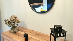 Un armari de fusta amb un ram de flors seques, un objecte negre i un farol negre.
