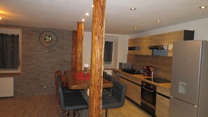Una cocina moderna con armarios de madera, un refrigerador de acero inoxidable y una zona de comedor con una mesa y sillas.