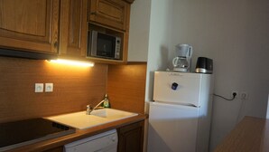 A compact kitchen with wooden cabinets, a microwave, a refrigerator, a coffee maker, and a dishwasher. - 4-room apartment, 9 pers, pets allowed, covered parking (Orcières Merlette)