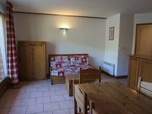 Ein Zimmer mit einem hölzernen Bett, einem Holztisch und einem Kleiderschrank.