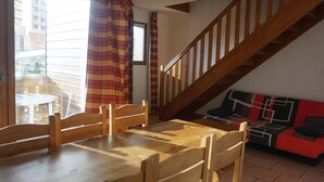 A dining area with a wooden table and chairs, a staircase, and a sofa with patterned cushions. - Duplex for 7/8 people 50m from slopes, pets allowed and parking (Orcières Merlette)