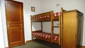 A bunk bed with a wooden frame and a striped mattress, a wooden wardrobe, and a closed door. - Duplex for 7/8 people 50m from slopes, pets allowed and parking (Orcières Merlette)