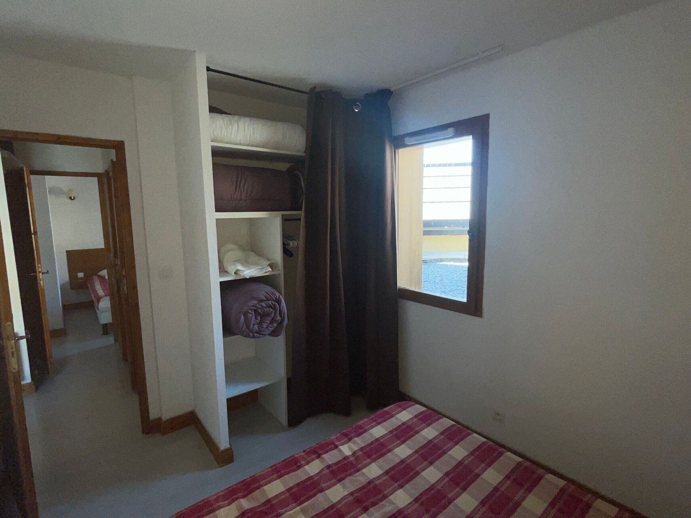 A bedroom with a bed, a wardrobe, and a window with a view.