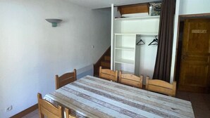 Ein Essbereich mit Holztisch und Stühlen, ein weißer Kleiderschrank mit Platz zum Aufhängen und eine Holztür.