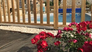 Una cerca de madera, una piscina y flores rojas.