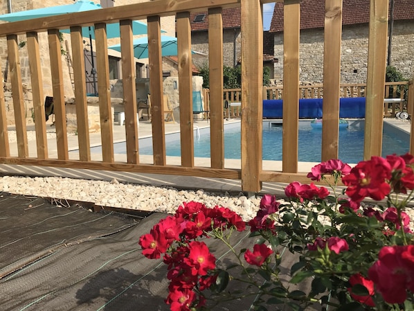 Una cerca de madera, una piscina y flores rojas.