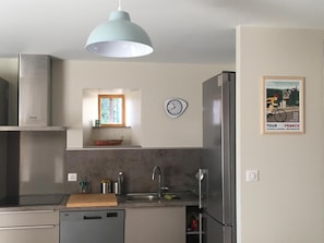 Una cocina compacta con diseño moderno, que cuenta con electrodomésticos de acero inoxidable, lavavajillas integrado y una lámpara colgante.