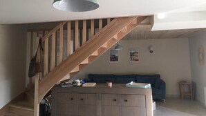 Una escalera con barandillas de madera que conduce a una sala de estar con un sofá azul y una pequeña mesa.
