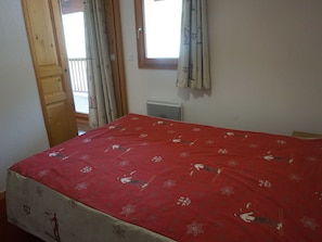A bedroom with a bed, a window, and a door.