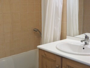 A bathroom with a bathtub, a sink, and wooden cabinets. - 3-Room Apartment for 6 in Quality Residence, Close to Shops and Slopes, Free WiFi, Pets Allowed (Orcières Merlette)