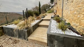 A stone building with a wooden deck and planters with plants and pebbles. - LE CLOS DE PEYRUZEL (Daglan)