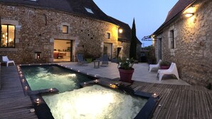 A stone building with a pool, outdoor seating, and a well-lit entrance. - LE CLOS DE PEYRUZEL (Daglan)