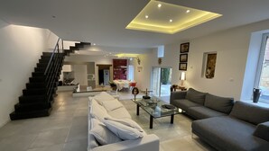 A modern living room with a staircase, a dining area, and a kitchen. - LE CLOS DE PEYRUZEL (Daglan)