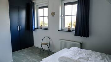 Une chambre à coucher avec un lit, un radiateur, une chaise et une armoire.