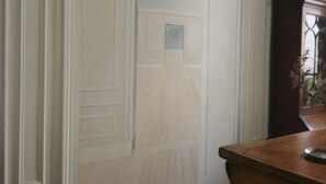 Una stanza con un comò in legno, una porta bianca con pannelli decorativi e un termosifone a parete.