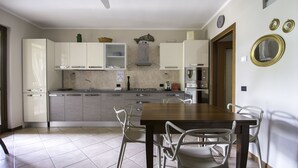 Een keuken met witte kasten, een houten eettafel en witte stoelen.