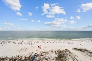 Ein Strand mit Volleyballnetz, amerikanischer Flagge und blauem Himmel.