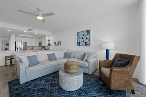 A modern living room with a light grey sectional sofa, a wicker chair, and a round coffee table.