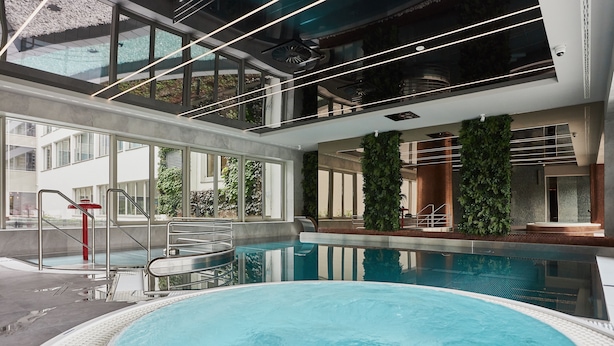 Une piscine intérieure avec des parois en verre transparent, un design moderne et une vue sur l’extérieur.