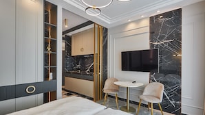 Une chambre d’hôtel moderne équipée d’un lit, d’une télévision, d’une petite table à manger et d’un mini-bar.