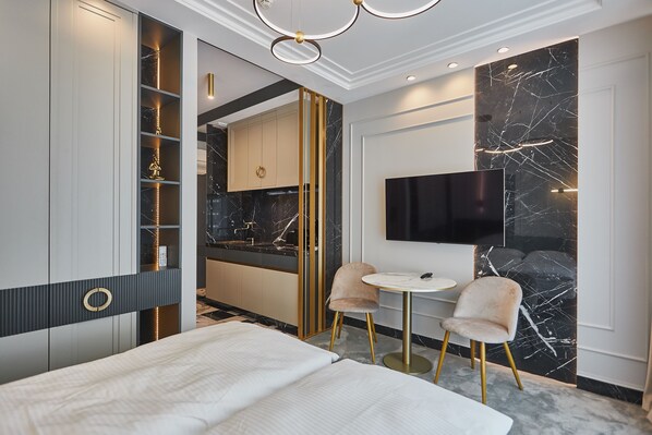 Una habitación de hotel moderna con una cama, un televisor, una pequeña mesa de comedor y un minibar.