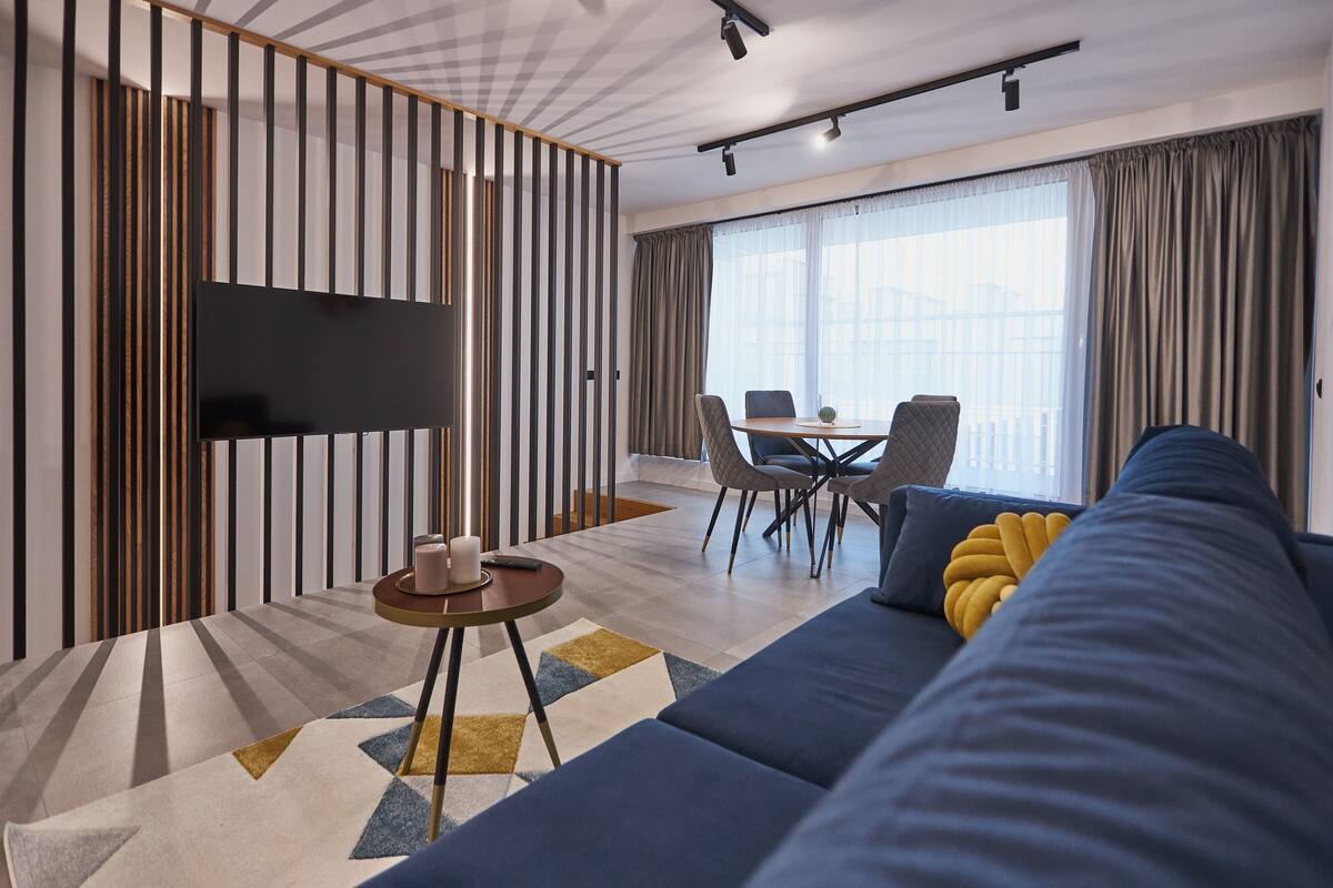 Een moderne woonkamer met een bank, een salontafel en een aan de muur bevestigde televisie.
