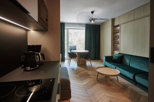 Una cocina moderna con cafetera, una mesa de comedor con sillas y un sofá verde en la sala.