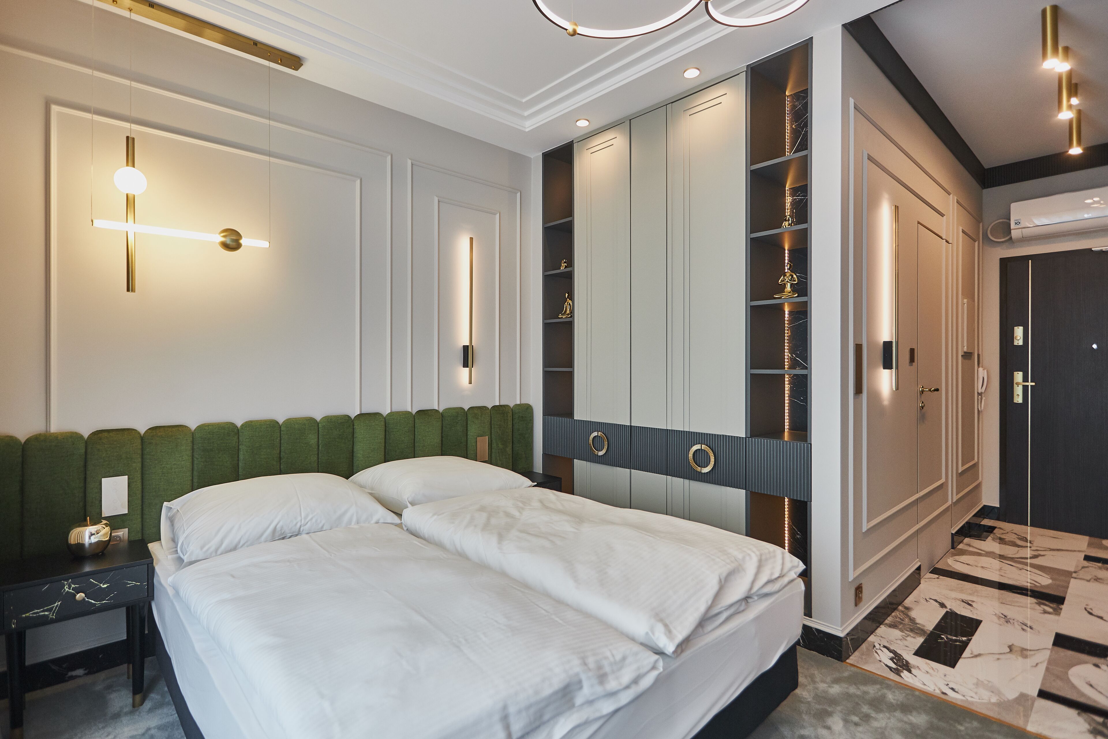 A modern hotel room with a large bed, built-in wardrobe, and a unique lighting fixture.