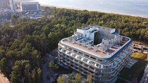 Un hôtel moderne à plusieurs étages, doté d’une terrasse sur le toit et offrant une vue sur la plage.