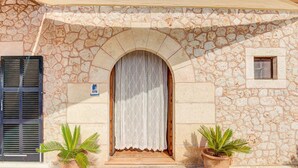 A stone building with a wooden door, two potted plants, and a small window. - Son Blai Petit by Rentallorca (Muro)