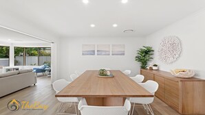 Un espace repas moderne avec une table en bois et des chaises blanches, un meuble en bois et un élément décoratif mural.