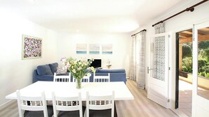 A bright living room with a white table, blue sofa, and a TV. There's a door leading to a balcony with plants. - Finca Sant Jordi, private pool, quiet location with a view, A/C, Wi-Fi (IB)