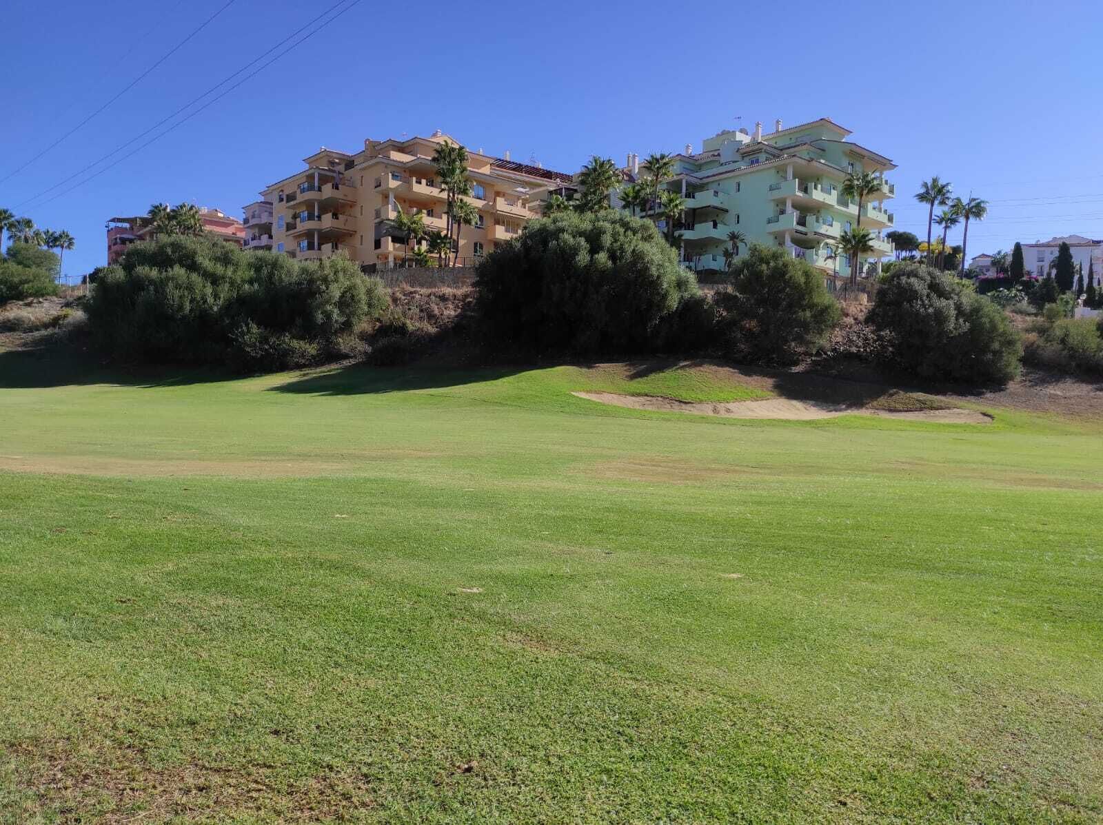 A golf course with a building complex in the background.