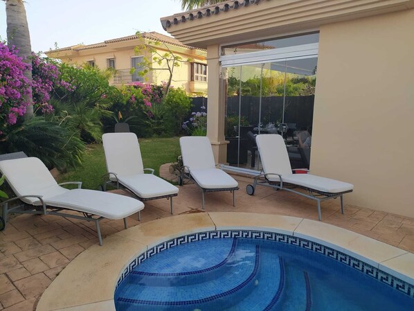 A pool area with lounge chairs and a glass-enclosed patio. - RIVIERA VILLA WITH PRIVATE POOL (Mijas Costa)