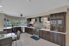 A modern kitchen with dark wood cabinets, stainless steel appliances, and a large island.