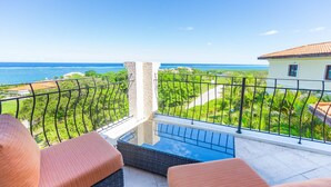 A balcony with wicker furniture and a view of the ocean. - Luxury at Pristine Bay Villa 1106 (Roatan)