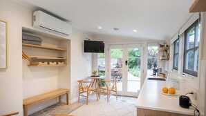 A modern kitchen with a dining area, built-in shelves, and a TV.