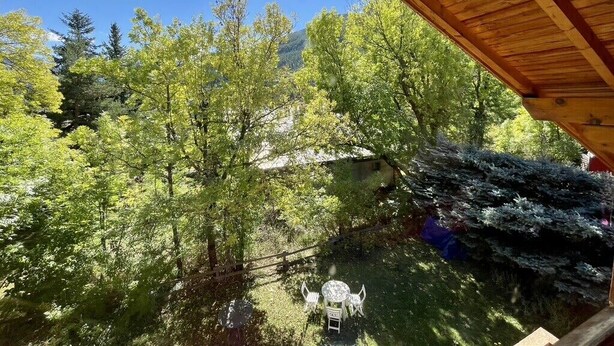 Una terraza de madera con vistas a un paisaje verde y exuberante, lleno de árboles.