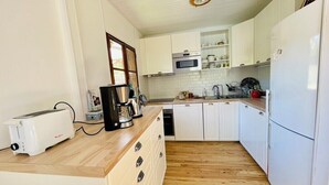 Cocina compacta con armarios blancos, microondas, tostadora y cafetera.