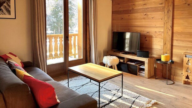 Ein gemütliches Wohnzimmer mit einer Couch, einem Couchtisch, einem Fernseher und einem Holz-TV-Möbel.