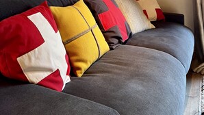 Ein graues Sofa mit bunten Kissen und einem gerahmten Bild an der Wand.