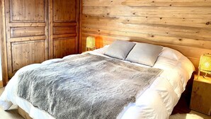 Ein Zimmer mit Holzwänden, einem Bett, einem Nachttisch und einem Kleiderschrank.
